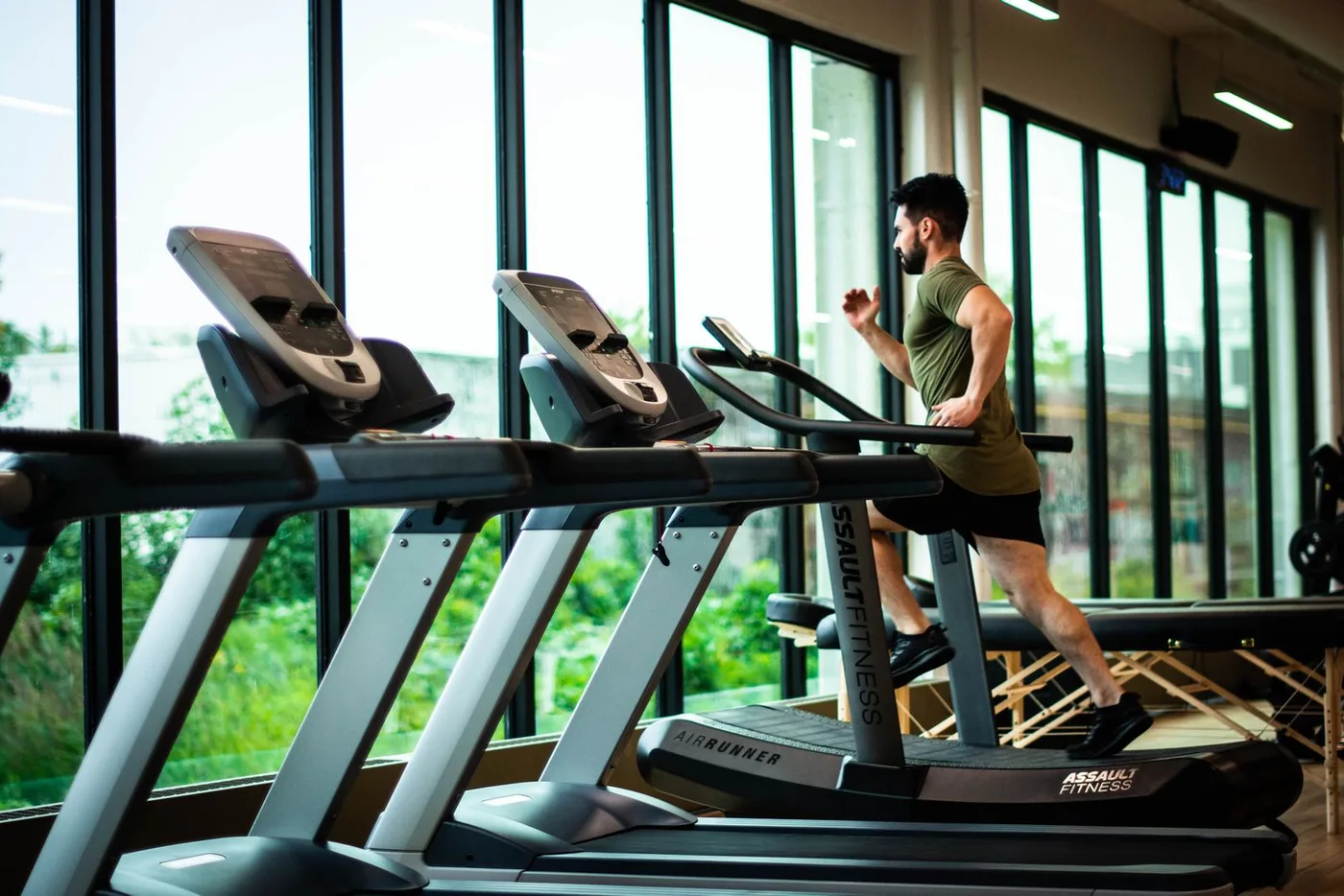 A man running on a treadmill in a bright modern gym